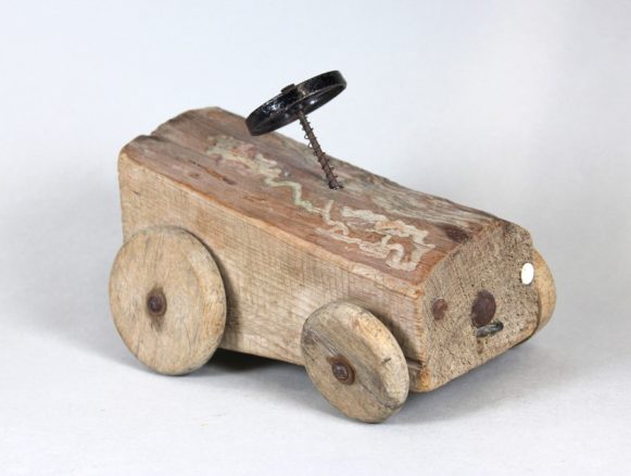 Bildnachweis: Museen der Stadt Nürnberg, Spielzeugmuseum Spielzeug-Auto aus einem Stück Brennholz, 1950er Jahre. 