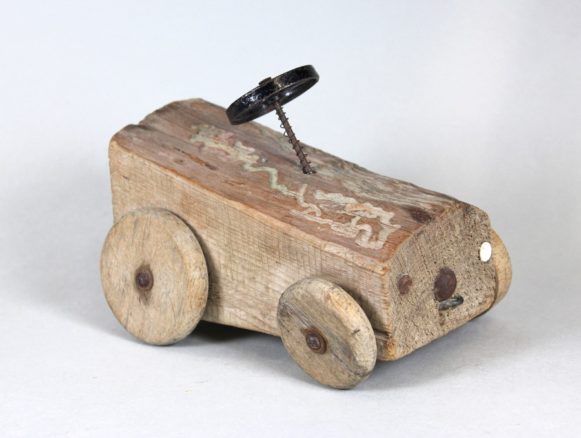 Bildnachweis: Museen der Stadt Nürnberg, Spielzeugmuseum Spielzeug-Auto aus einem Stück Brennholz, 1950er Jahre.